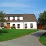 A traditional farmhouse with flowers in the windows and a well-tended garden.