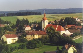 Aerial view of Waldkirchen an der Thaya with church and surrounding houses, surrounded by fields and forests.