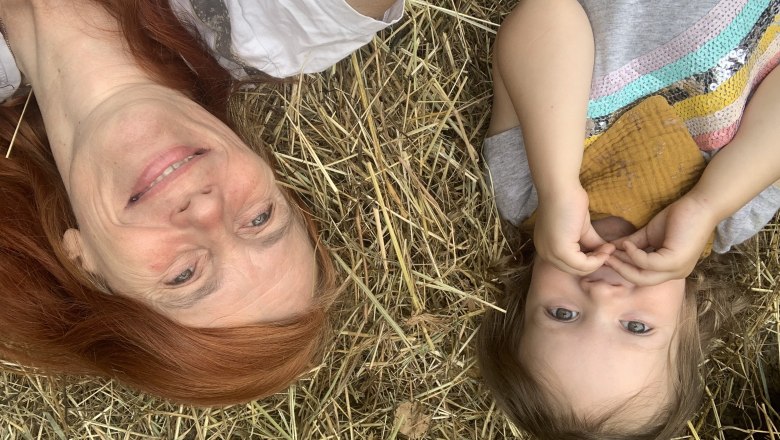 Two people lie smiling on hay, an adult and a child.
