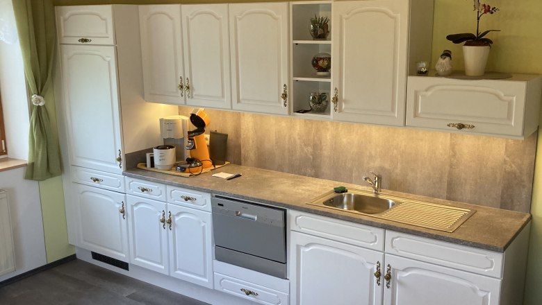 Kitchen with white cupboards, dishwasher and sink.