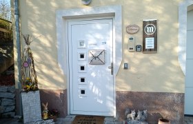 Entrance area of a house with decorative elements such as a rabbit, a welcome sign and flowers.