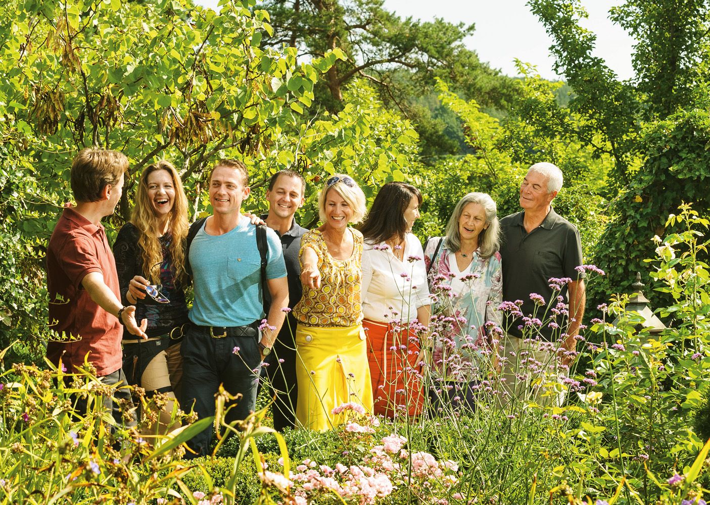 A group of people stand smiling in a blooming garden.
