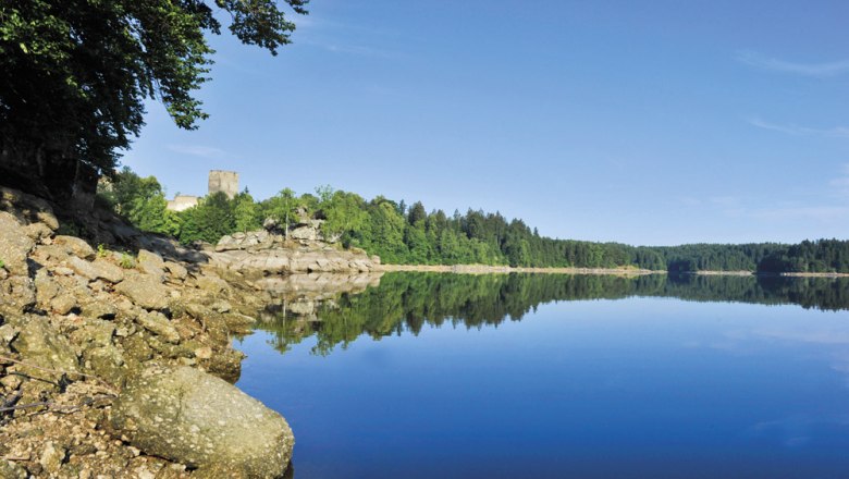 Kampsee Ottenstein with calm water, wooded shores and a castle in the background.