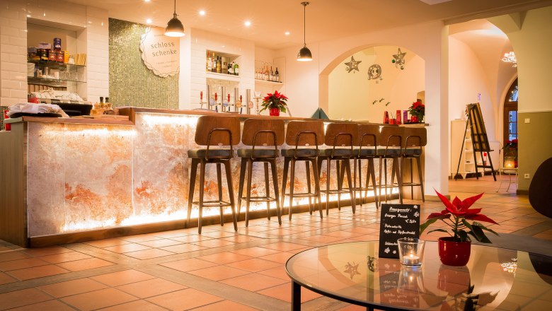 Elegant bar with illuminated counter and high stools, decorated with poinsettias.
