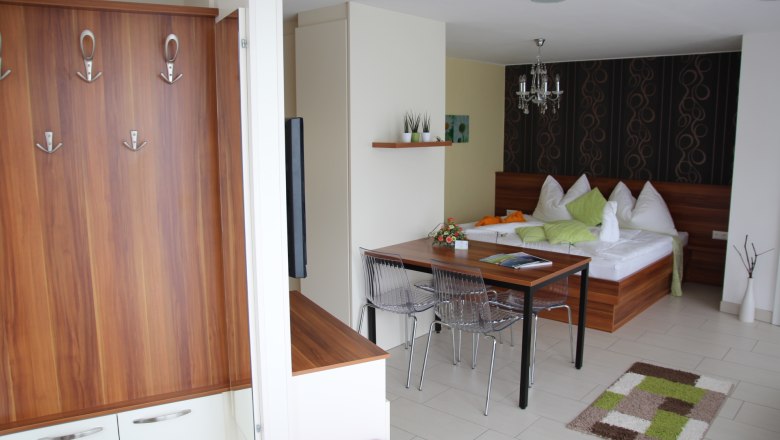 Modern apartment with wooden furniture, dining table, bed and decorative elements.