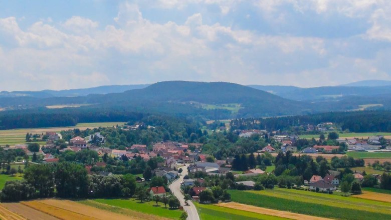 Landscape photograph of Wartmannstetten in summer with fields and hills in the background.