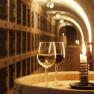 Two wine glasses and a candle on a barrel in a wine cellar.