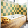 Bathroom with bathtub, yellow-green tiles and wood paneling.