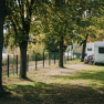 Caravan on a green pitch under trees.