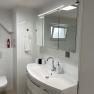 Modern bathroom with washbasin, mirror, toilet and small window.