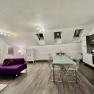Modern loft with open kitchen, dining table and purple sofa.