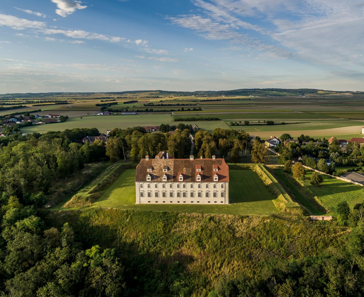 Aerial view of Schloss Stetteldorf am Wagram surrounded by green countryside and fields.