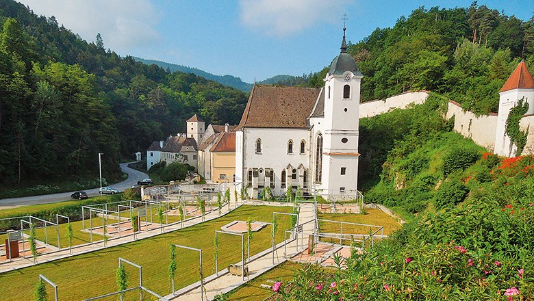 Historic Aggsbach Charterhouse in a green, hilly landscape.