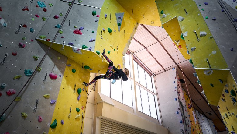 Person climbing on an indoor climbing wall with colorful holds.