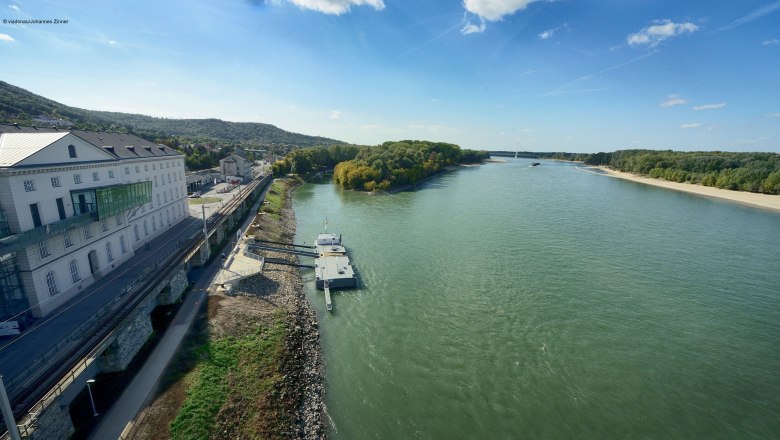 View of the Danube at Hainburg with landing stage and buildings on the bank.