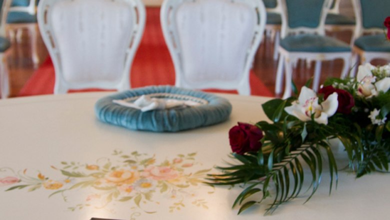 An elegant room with white chairs and a wedding folder on a table.