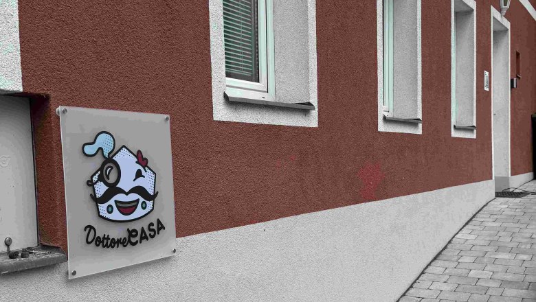 Exterior view of a building with a red façade and a sign reading 'Dottore Casa'.