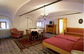 Comfortable room with wooden furniture, double bed, dining table and TV.