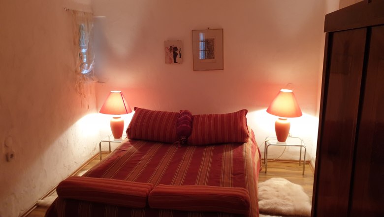 Cozy bedroom with double bed, red lamps and wooden furniture.