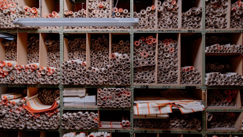 Shelf with many rolled paper documents in compartments.
