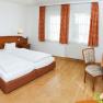 A cozy double room with two beds, wooden furniture and a desk with chair.
