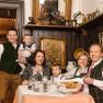 A family in traditional dress sits at a table in a rustic restaurant.