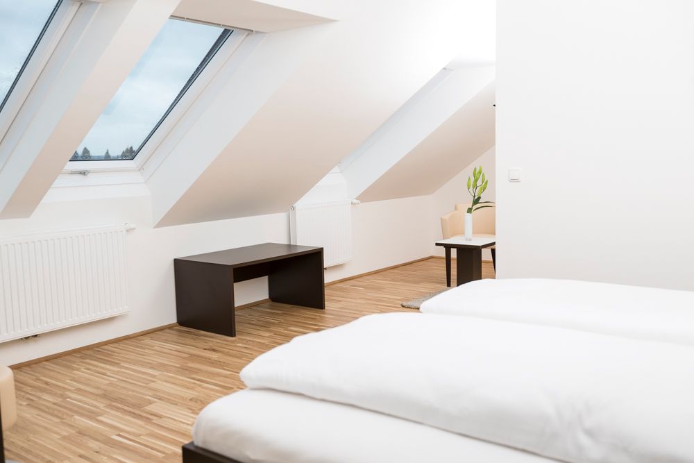 Modern guest room with skylights, wooden floor and minimalist furnishings.