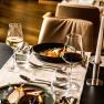 Elegant restaurant table with wine glasses, candle and gourmet dishes.
