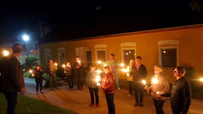 People stand in front of a yellow building at night with torches.