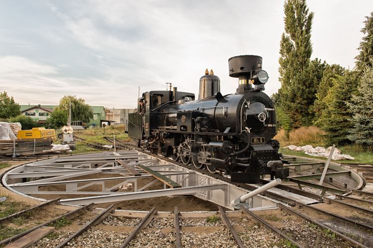 A black steam locomotive on a turntable outside.