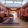 Interior view of a living room with red walls, leather sofa, wooden table and colorful carpet.