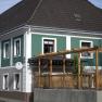 Exterior view of a bed and breakfast with green and white façade and wooden pergola.