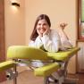 Woman in a bathrobe lying smiling on a green massage table in a wellness room.