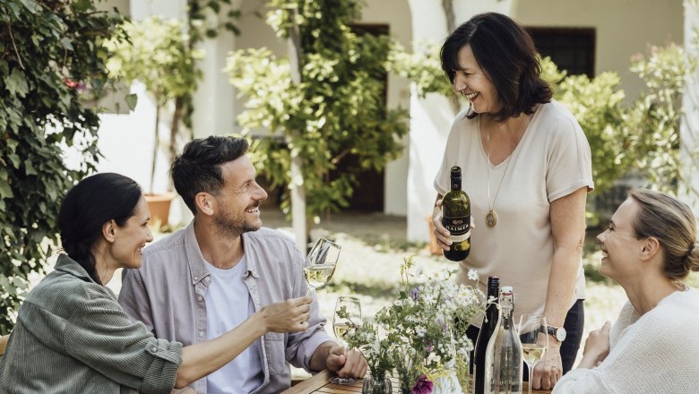 Genießerhof Haimer, © Weinviertel Tourismus GmbH / Sophie Menegaldo Four people sit at an outdoor table and enjoy wine and bread.