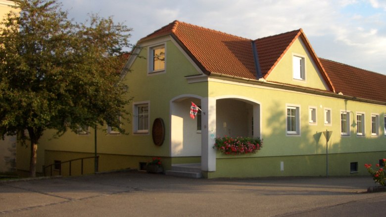 Yellow building with a red roof and flowers at the entrance.
