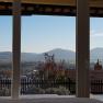 View from a window of a hilly landscape with a monastery on a hill in the background.
