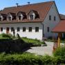 A traditional white country house with a red roof and garden.