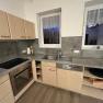 Modern kitchen with wooden cupboards, electric stove, sink and dishwasher.