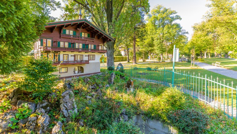 Miniature house in a park with trees and a path.