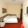 A hotel room with a double bed, red carpeting and a flat-screen TV on the wall.
