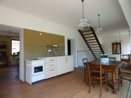 Interior view of a living room with kitchen, dining table and staircase.