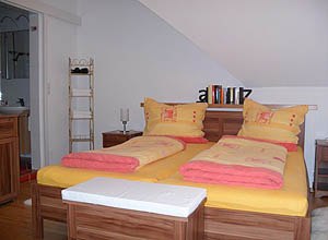 Cozy bedroom with double bed and yellow-red bed linen.