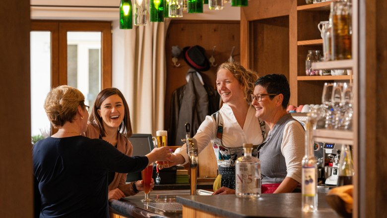 Four women are laughing and chatting at a bar.