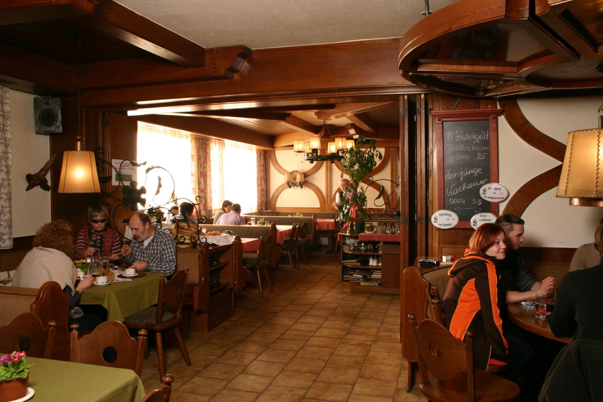 Cozy restaurant with wooden furniture and guests at tables.