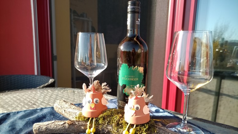 Wine bottle with two empty glasses and decorative figures on a table.