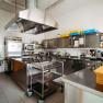 Modern commercial kitchen with stainless steel appliances and work surfaces.
