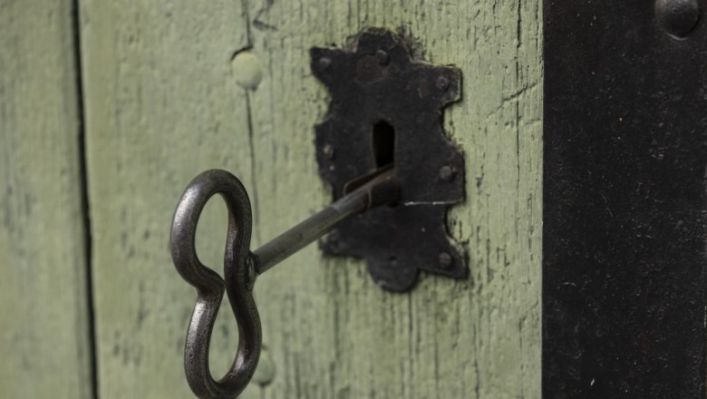 Close-up of an old key in a green wooden door lock.