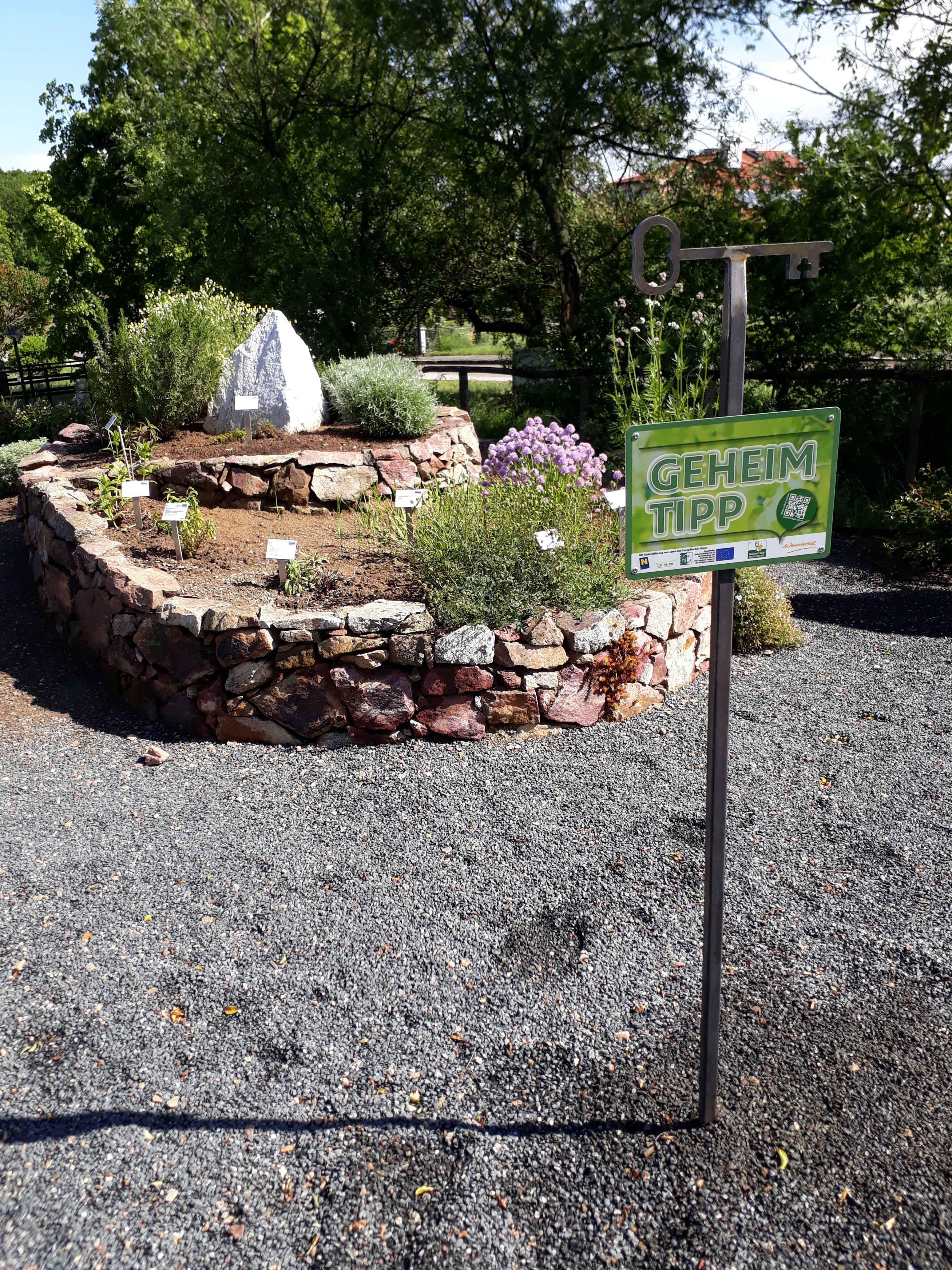 Herb spiral made of stones with plants and a sign with the inscription 'Insider tip'.