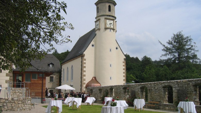Church with tower and garden with bar tables, wedding scene.