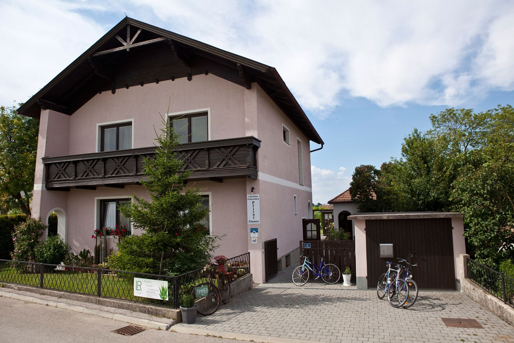 Street view of the house with well-kept front garden and driveway with garage.